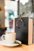 Free photo close-up of coffee with spectacles and book on wooden desk