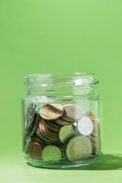 緑色の背景にガラス容器内のコインのクローズアップ