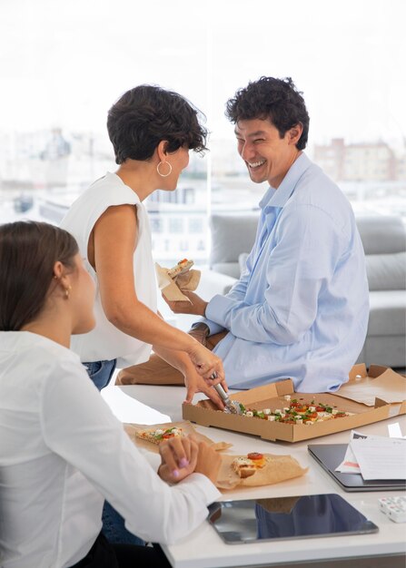 Close up colleagues eating pizza