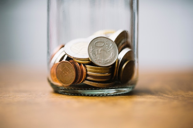 Крупный план собранных монет в стеклянной банке на столе