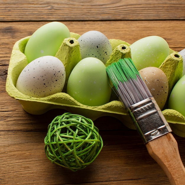 Close-up of colored easter eggs in carton with paint brush and decoration