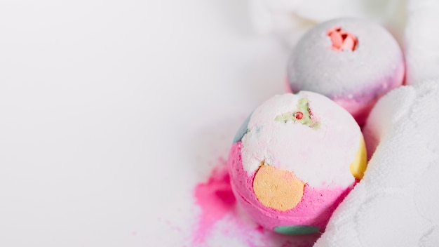 Foto gratuita primo piano di bombe da bagno colorati e tovagliolo su sfondo bianco