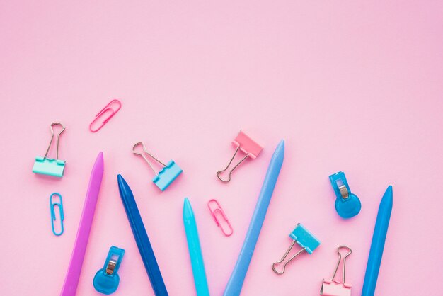 Close-up of colorful crayon color and paper clip against pink background