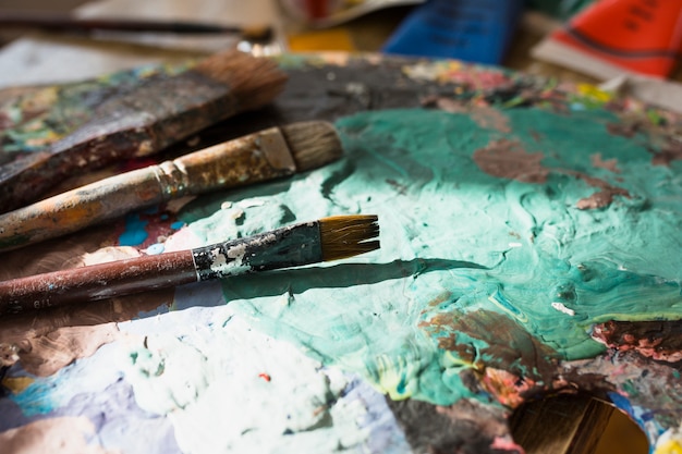 Close-up of colorful messy old paint brush and palette