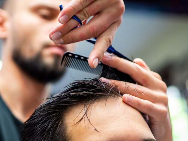 Close-up of comb in hands with blurred hairdresser