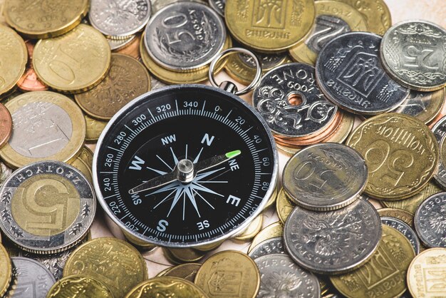 Close-up of compass surrounded by different coins