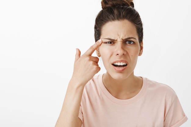 Close-up of confused and upset girl posing against the white wall