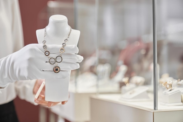 Крупный план рук консультанта, представляющих ожерелье в магазине