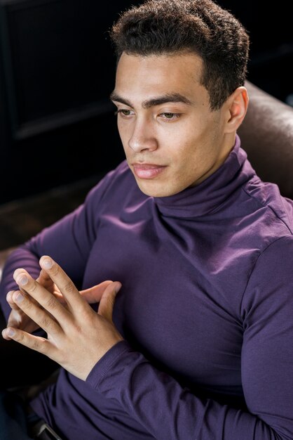 紫色のポロの首のtシャツで熟考されたハンサムな若い男のクローズアップ
