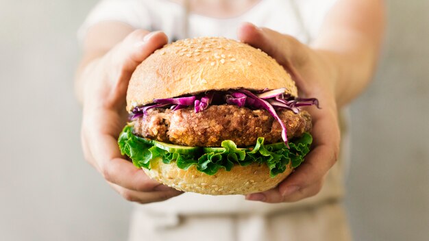 Close-up cook holding burger in hands