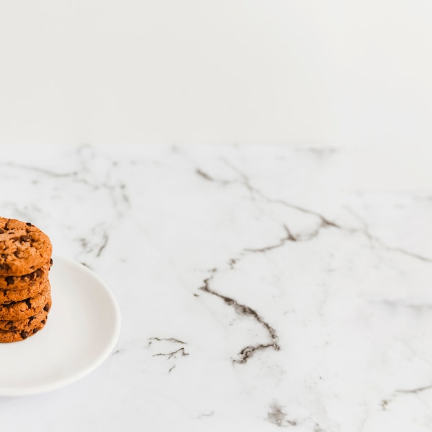 Close-up of cookies stack on white plate over the marble backdrop