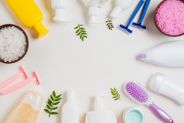Close-up of cosmetics products; razor; salt and hairbrush on white background