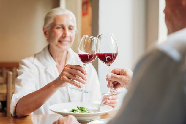 Close-up couple clinking glasses with red wine