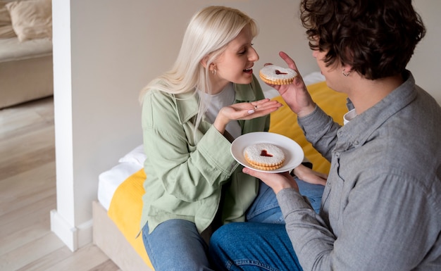 Free photo close up couple eating cookies