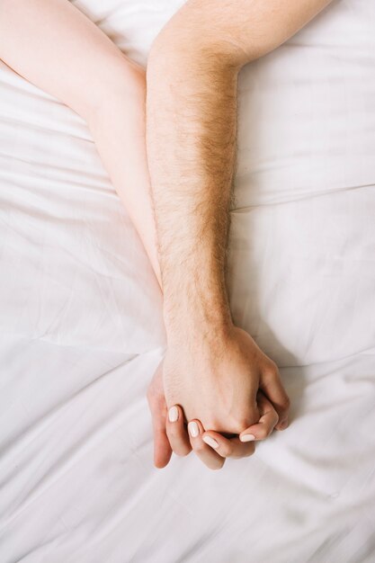 ベッドで手を繋いでいるカップルのクローズアップ