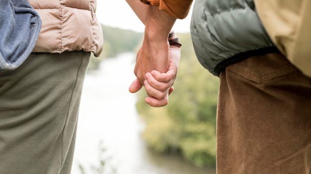 Close-up couple holding hands near river