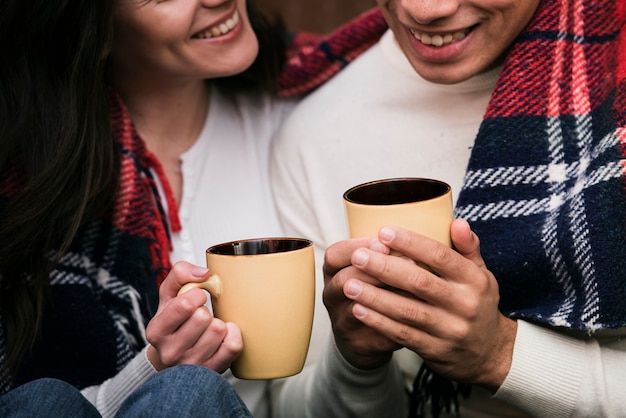 Close-up couple holding hot drinks Free Photo