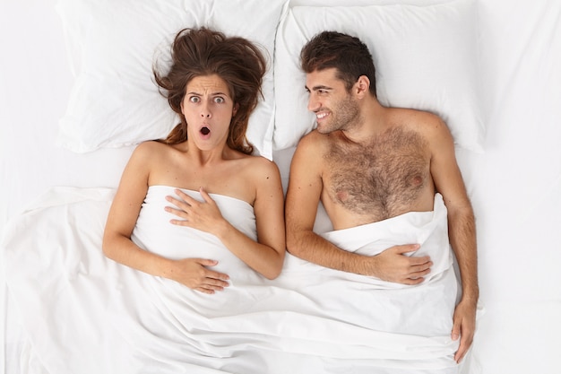 Free photo close up on couple lying in bed under white blanket