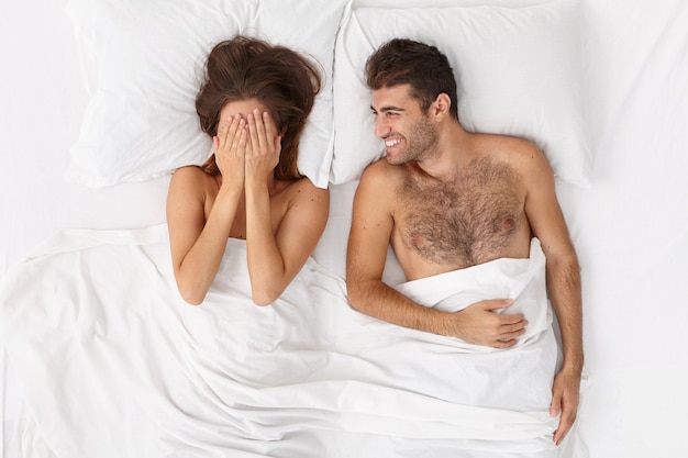 Free photo close up on couple lying in bed under white blanket