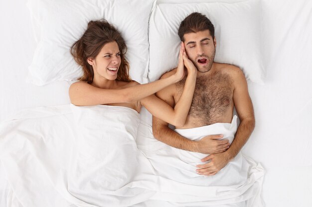 Close up on couple lying in bed under white blanket