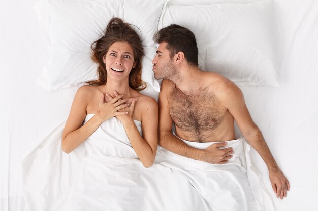 Close up on couple lying in bed under white blanket