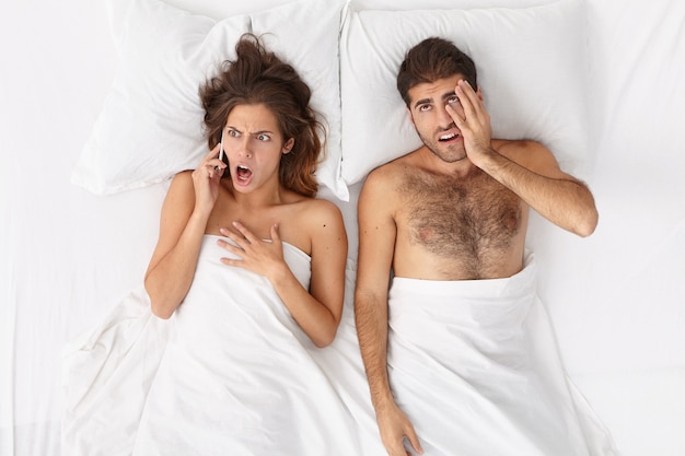 Free photo close up on couple lying in bed under white blanket