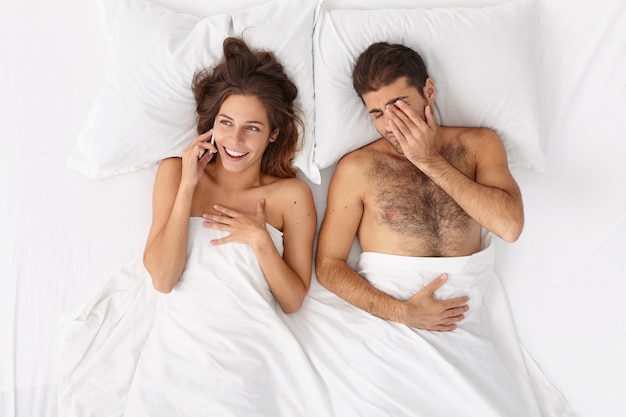 Close up on couple lying in bed under white blanket