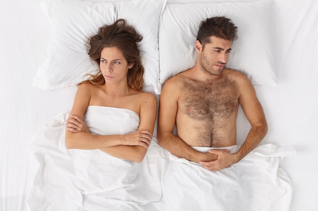 Close up on couple lying in bed under white blanket