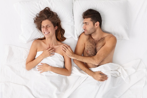Foto gratuita primo piano sulla coppia sdraiata a letto sotto il manto bianco