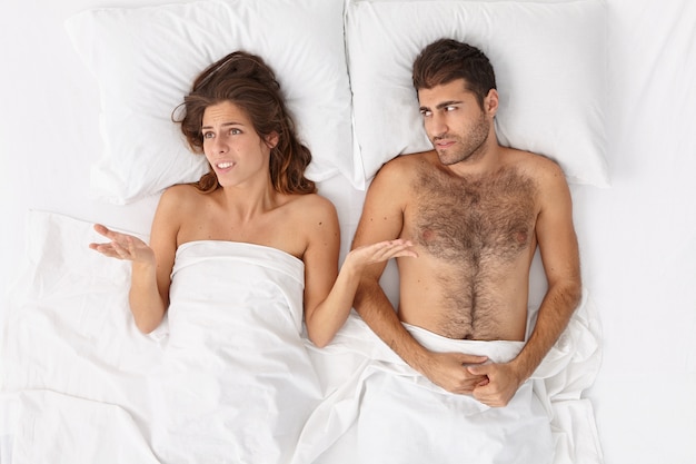 Free photo close up on couple lying in bed under white blanket