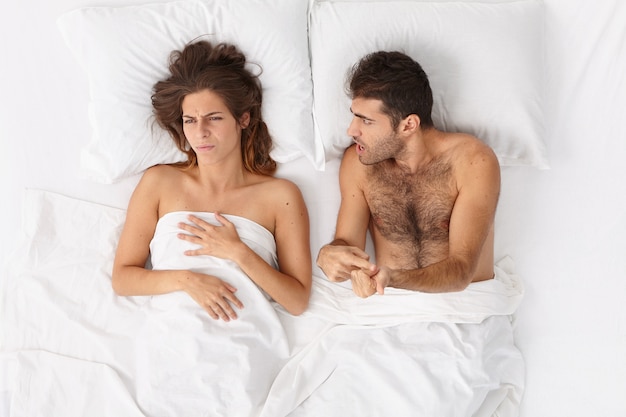 Close up on couple lying in bed under white blanket