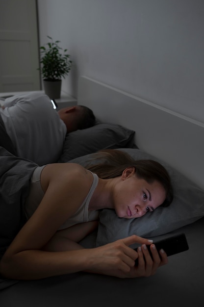 Close up on couple on phones in bedroom