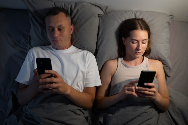 Free photo close up on couple on phones in bedroom