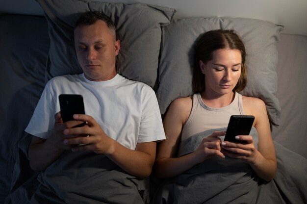 Close up on couple on phones in bedroom