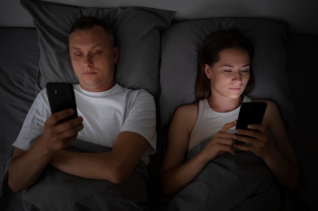 Close up on couple on phones in bedroom