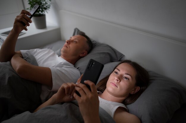 Close up on couple on phones in bedroom