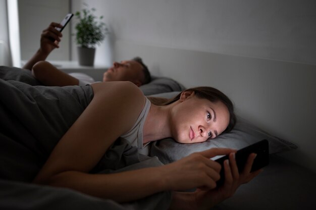 Close up on couple on phones in bedroom