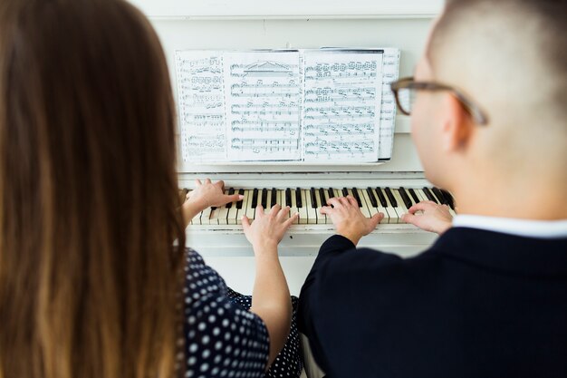 楽譜とピアノを弾くカップルのクローズアップ