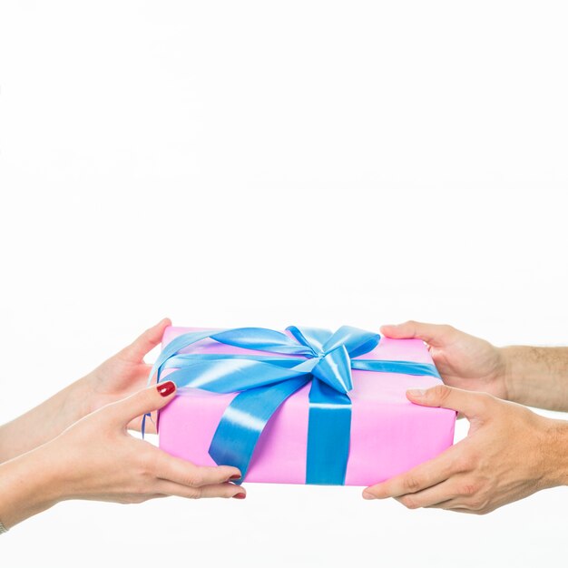 Close-up of couple's hand holding gift box on white background