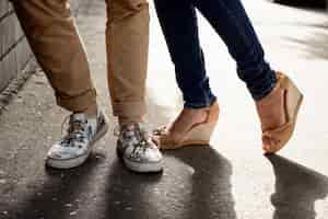 Free photo close up of couple's legs in keds standing at street.