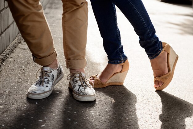 Close up of couple's legs in keds standing at street.