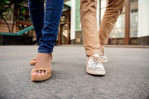 Close up of couple's legs in keds walking down street.