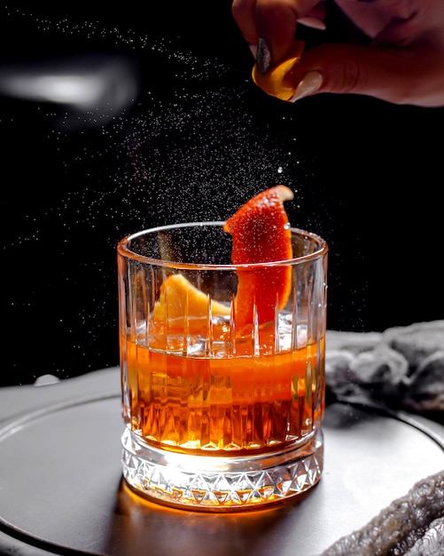 Close up of crystal viski glass with alcohol cocktail garnished with orange zest