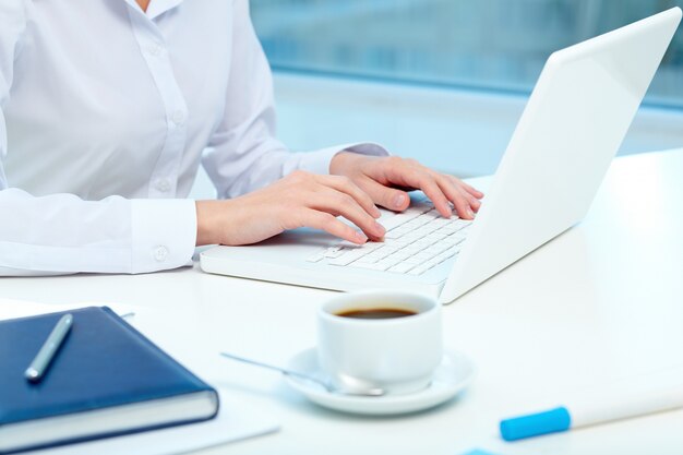 Close-up of cup of coffee and laptop