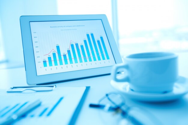 Close-up of cup of coffee with tablet background