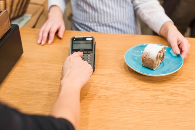 Free photo close-up of customer using pin machine to pay the bill for the delicious cake slice