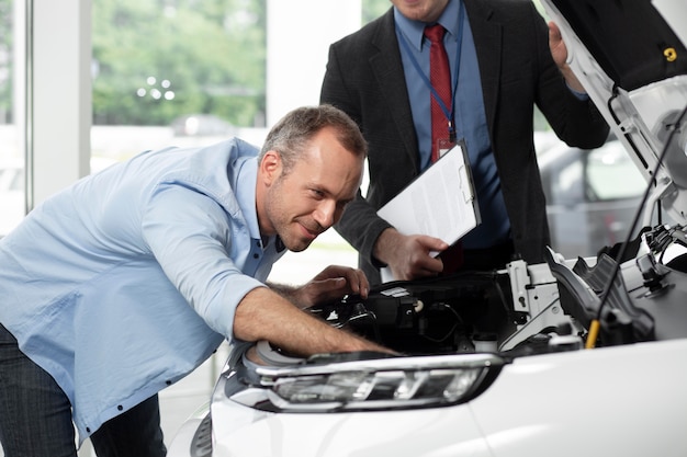 Foto gratuita primo piano sul cliente con un uomo d'affari in una concessionaria d'auto