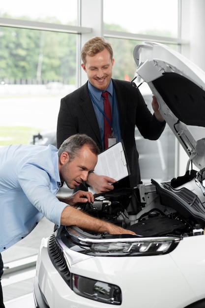 Foto gratuita primo piano sul cliente con un uomo d'affari in una concessionaria d'auto