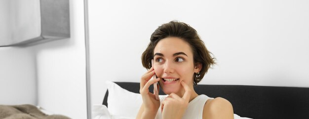 Free photo close up of cute brunette woman calling someone looking excited listening to friend over the phone