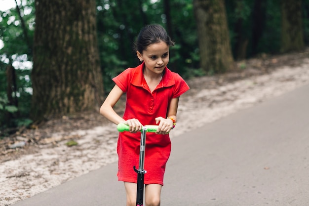 Close-up of a cute girl riding on push scooter